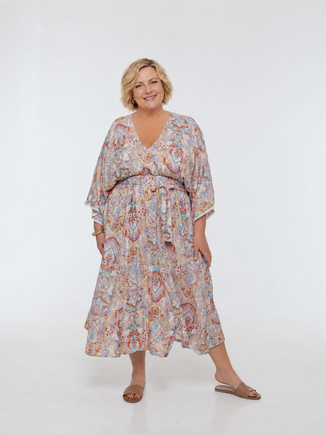 Woman wearing the Bianca Dress in Palazzo Print. A flowing dress with a wrap-over neckline, elasticated high waist, kimono sleeves and front split.