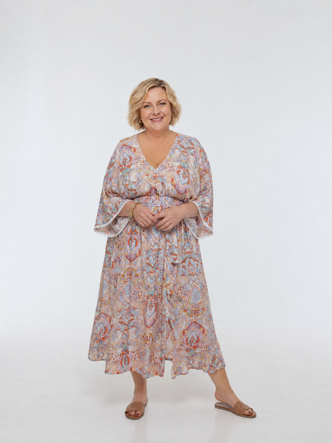 Woman wearing the Bianca Dress in Palazzo Print. A flowing dress with a wrap-over neckline, elasticated high waist, kimono sleeves and front split.