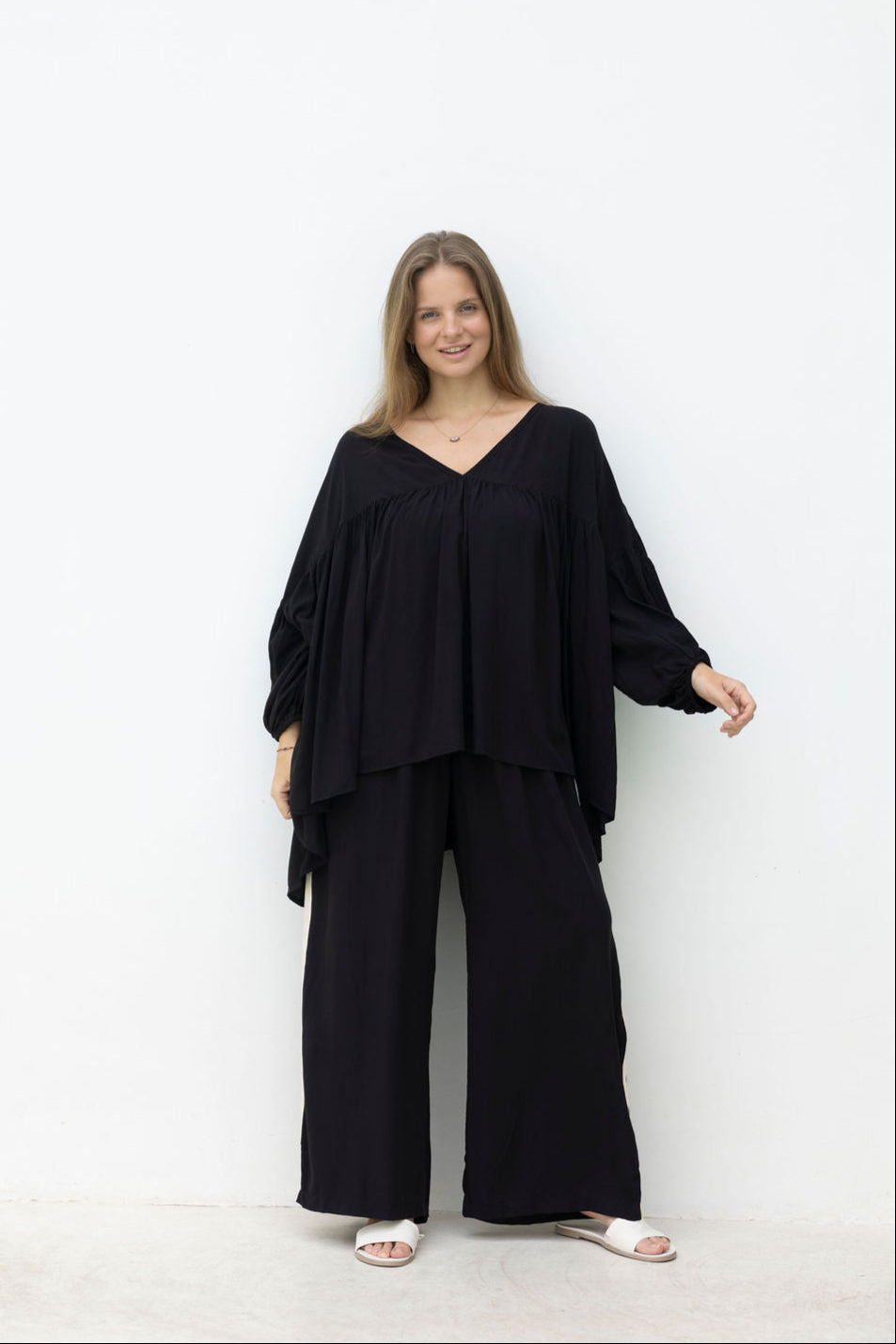 Woman wearing a black outfit standing against a white background