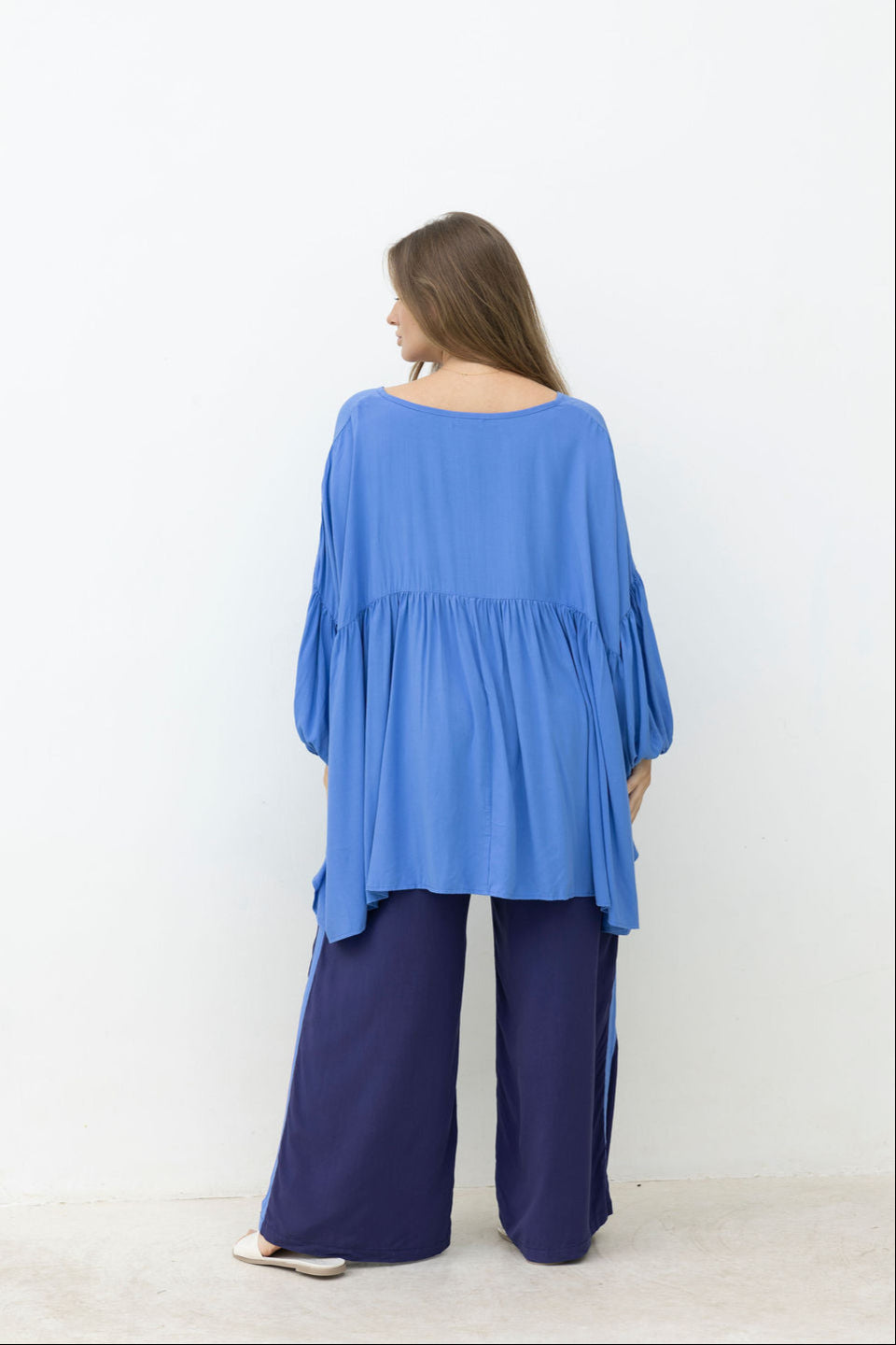 Woman wearing a blue outfit with wide-leg pants against a white background