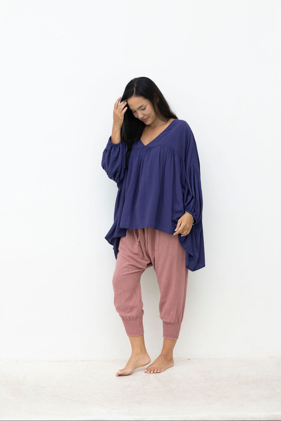 Woman wearing a long navy top with a dusty pink pant on a white background