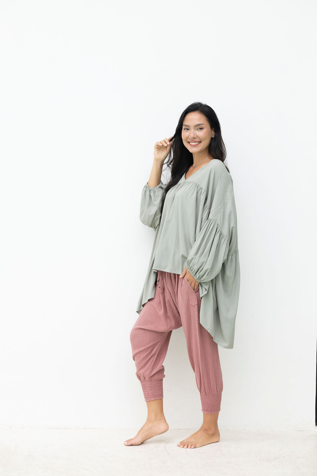 Woman wearing a green top and pink pants on a white background