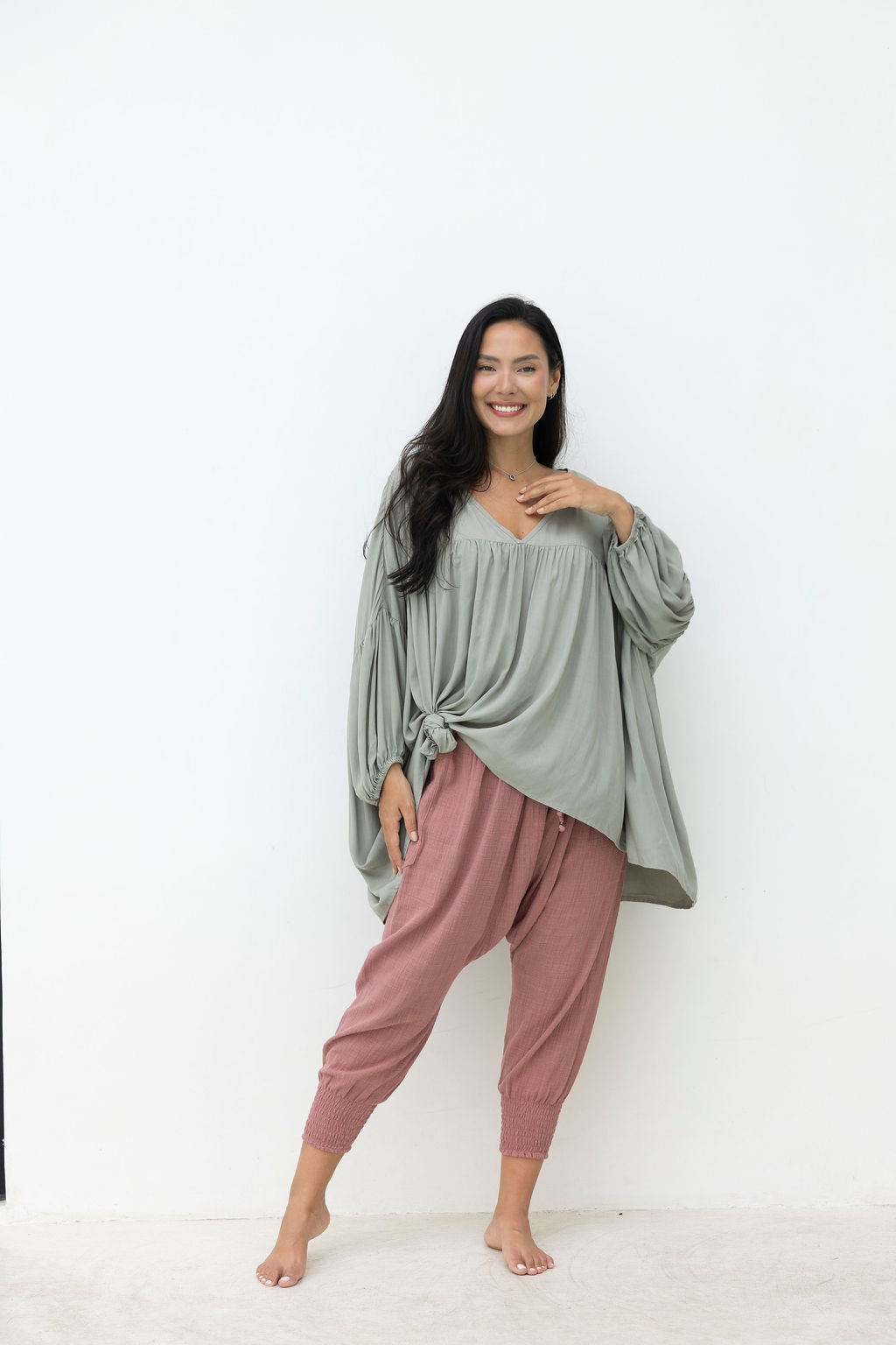Woman wearing a green top and pink pants on a white background