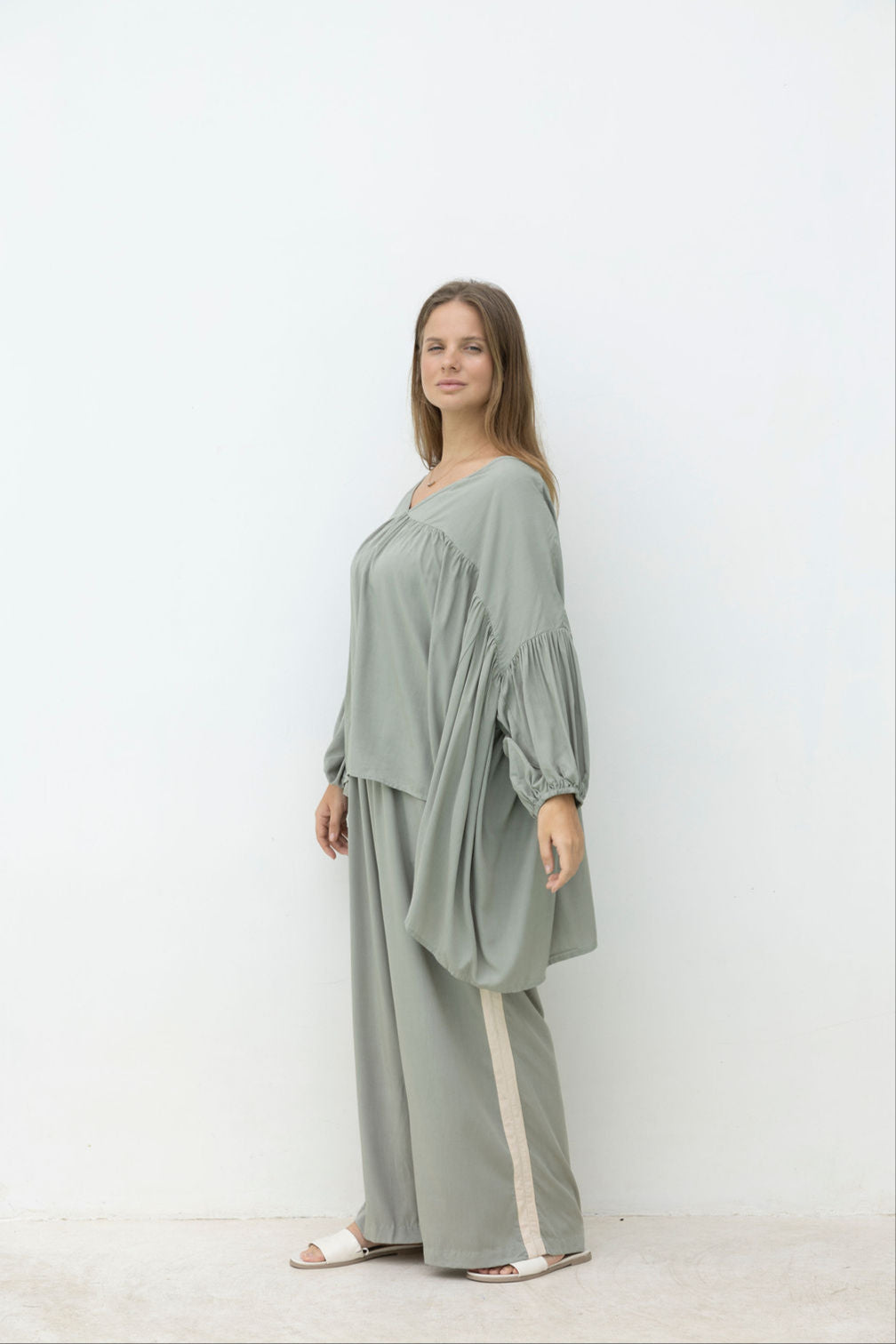 Woman wearing a light green top & panta white background