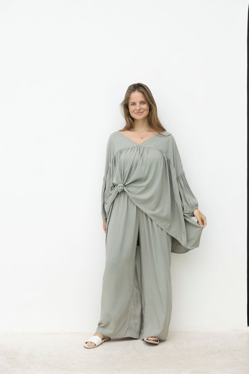 Woman wearing a light gray dress against a white background