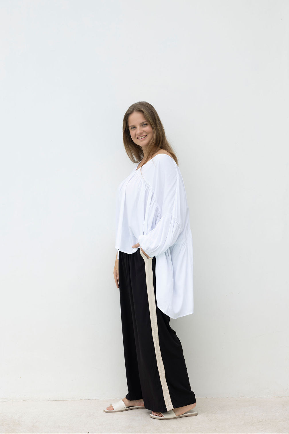 Woman wearing a white blouse and black pants with a white background