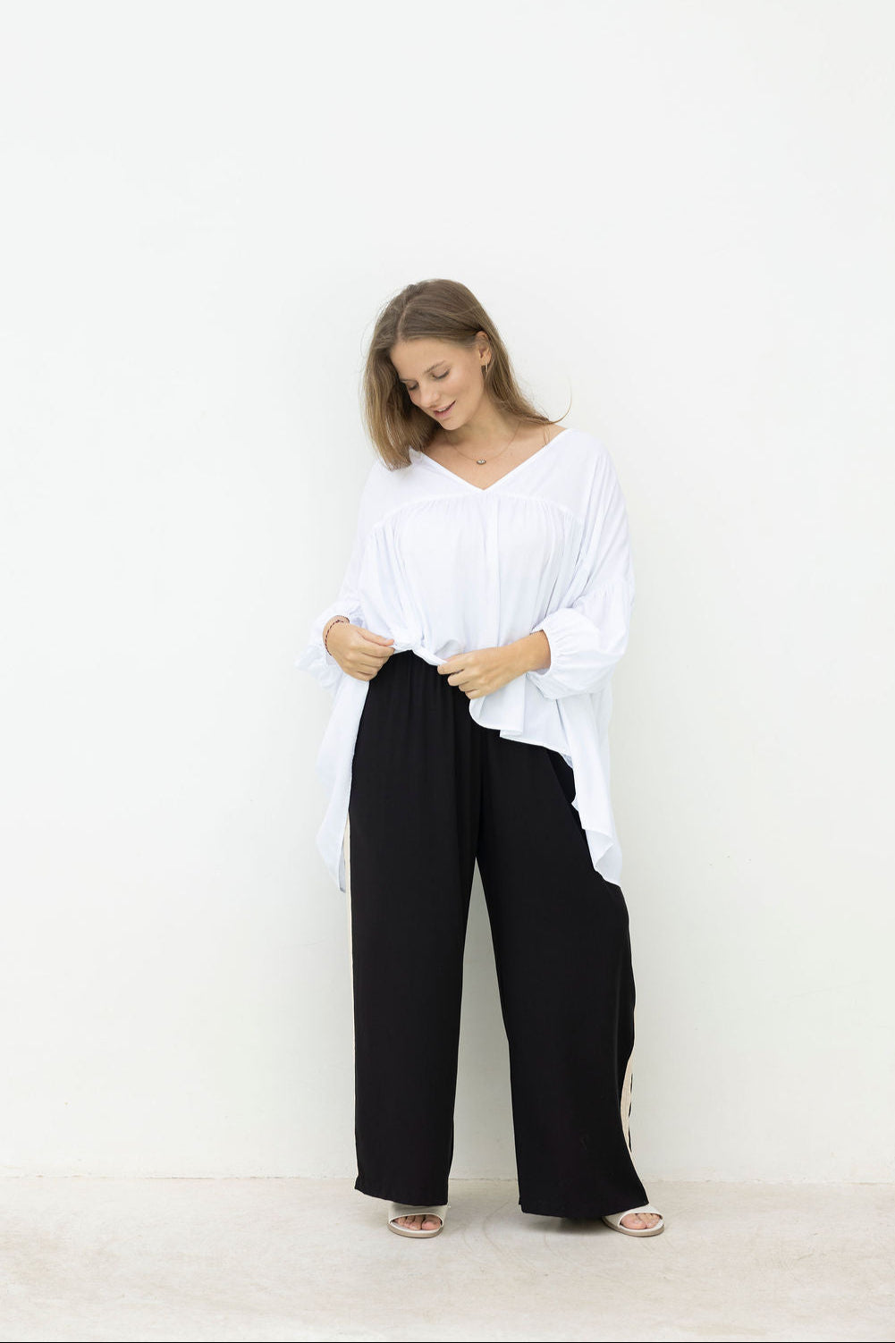Woman wearing a white top and black pants on a white background