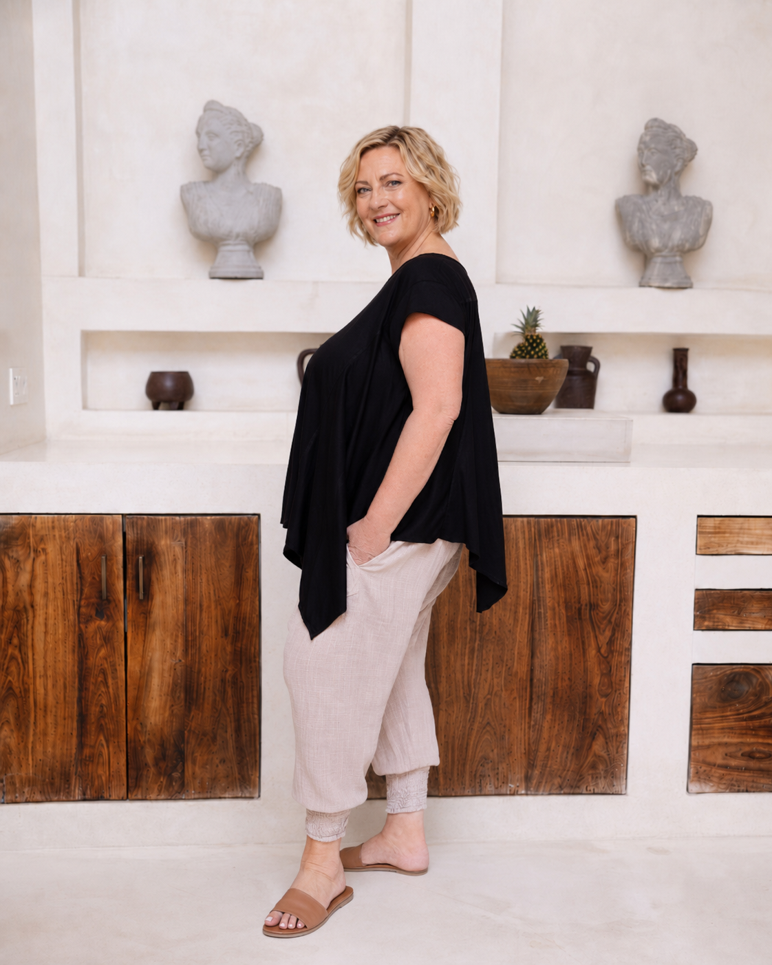 Woman wearing Little Cove Top in Black. Relaxed oversized fit, asymmetric hemline, 100% cotton.