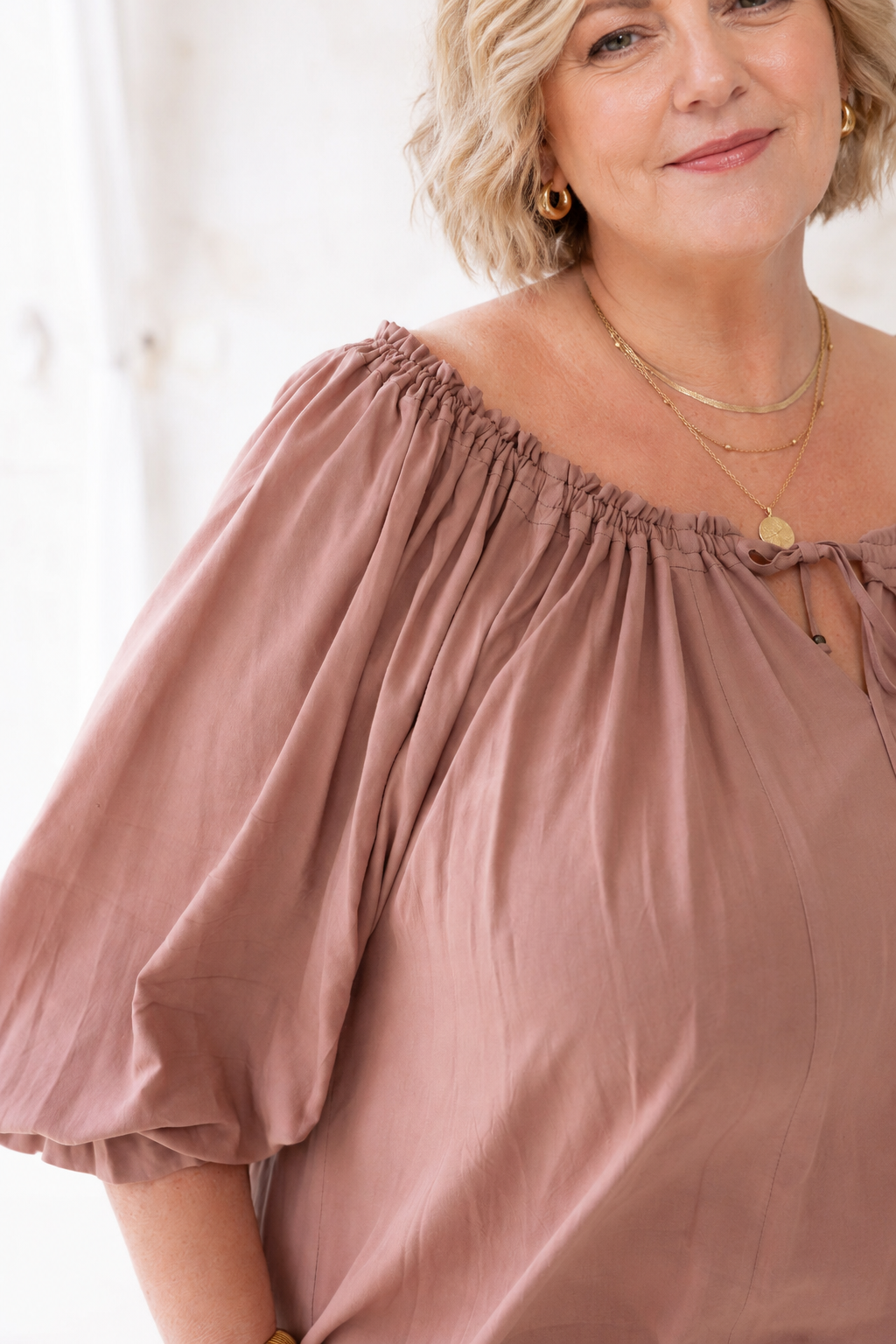 Woman wearing Ouvea Blouse in Mocca, relaxed fit, on or off-shoulder styling