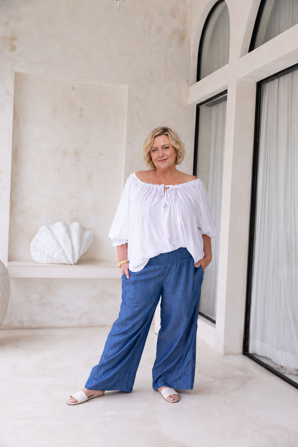Woman wearing Ouvea Blouse in White, relaxed fit, on or off-shoulder styling
