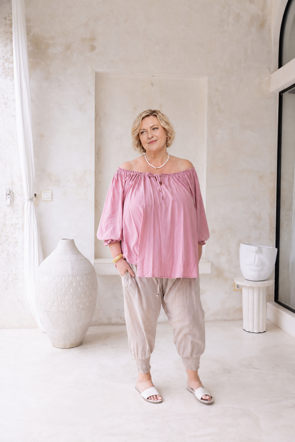 Woman wearing Ouvea Blouse in Dusty Pink, relaxed fit, on or off-shoulder styling