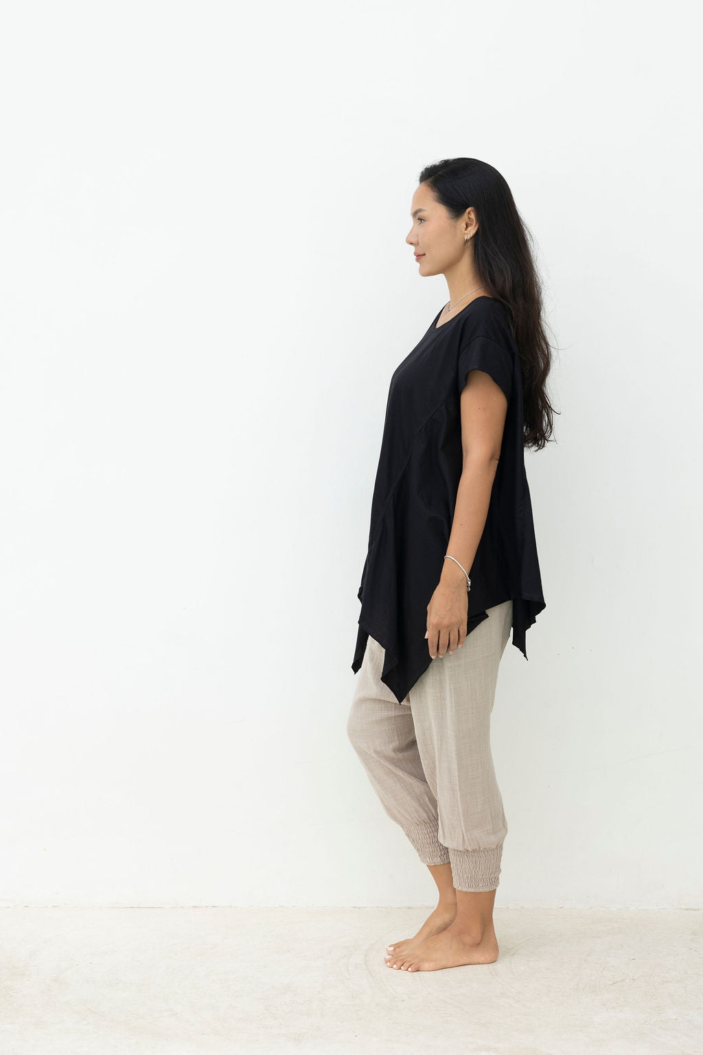 Woman wearing a black top and gray pants on a white background