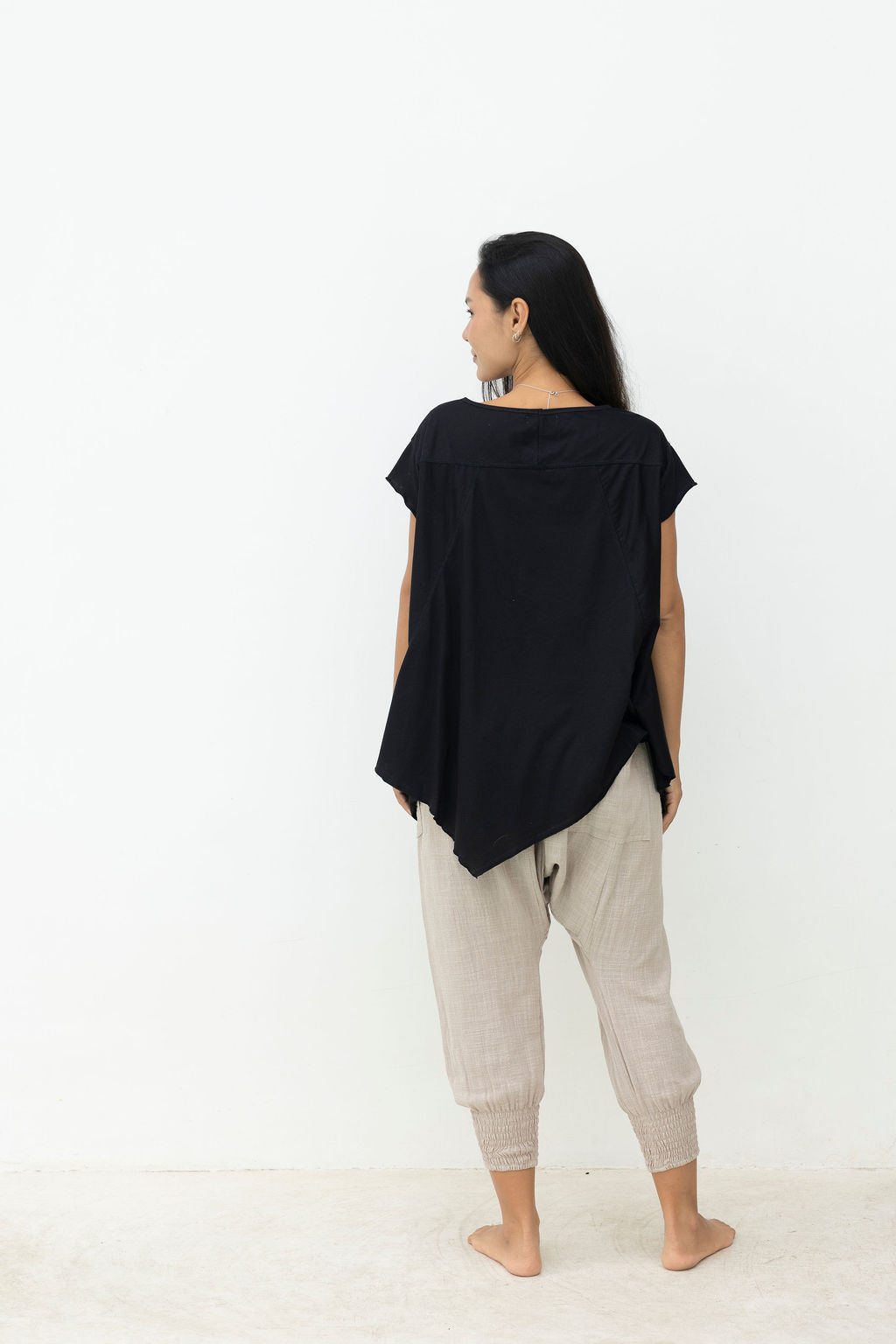 Person wearing a black top and gray pants on a white background