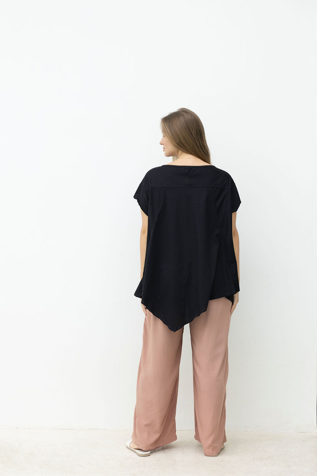 Woman wearing a black top and pink pants on a white background