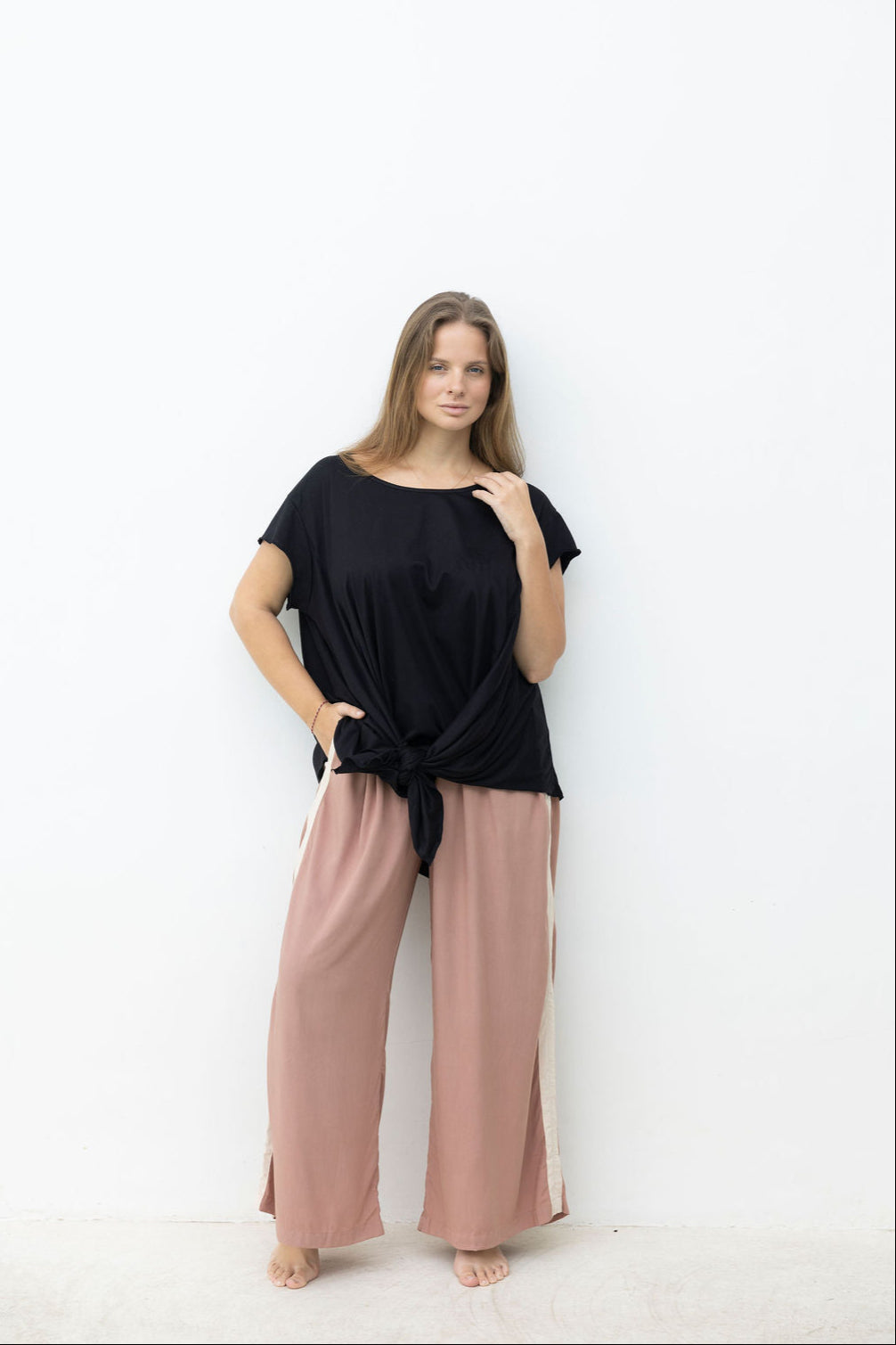 Woman wearing a black top and pink pants on a white background