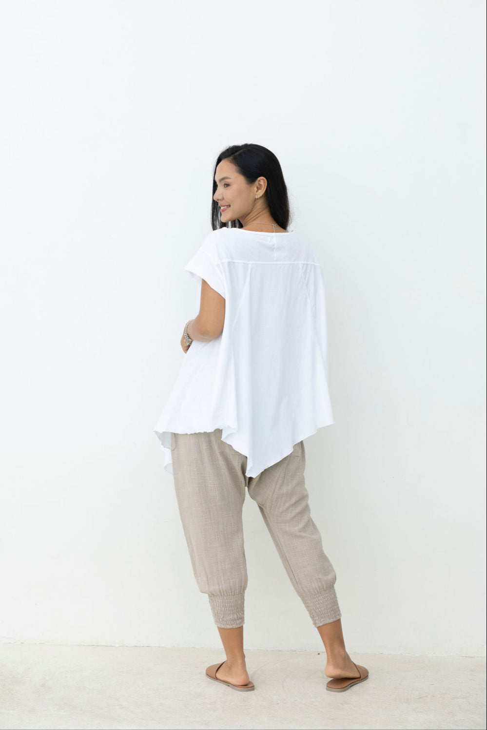 Woman wearing a white top and beige pants against a white background