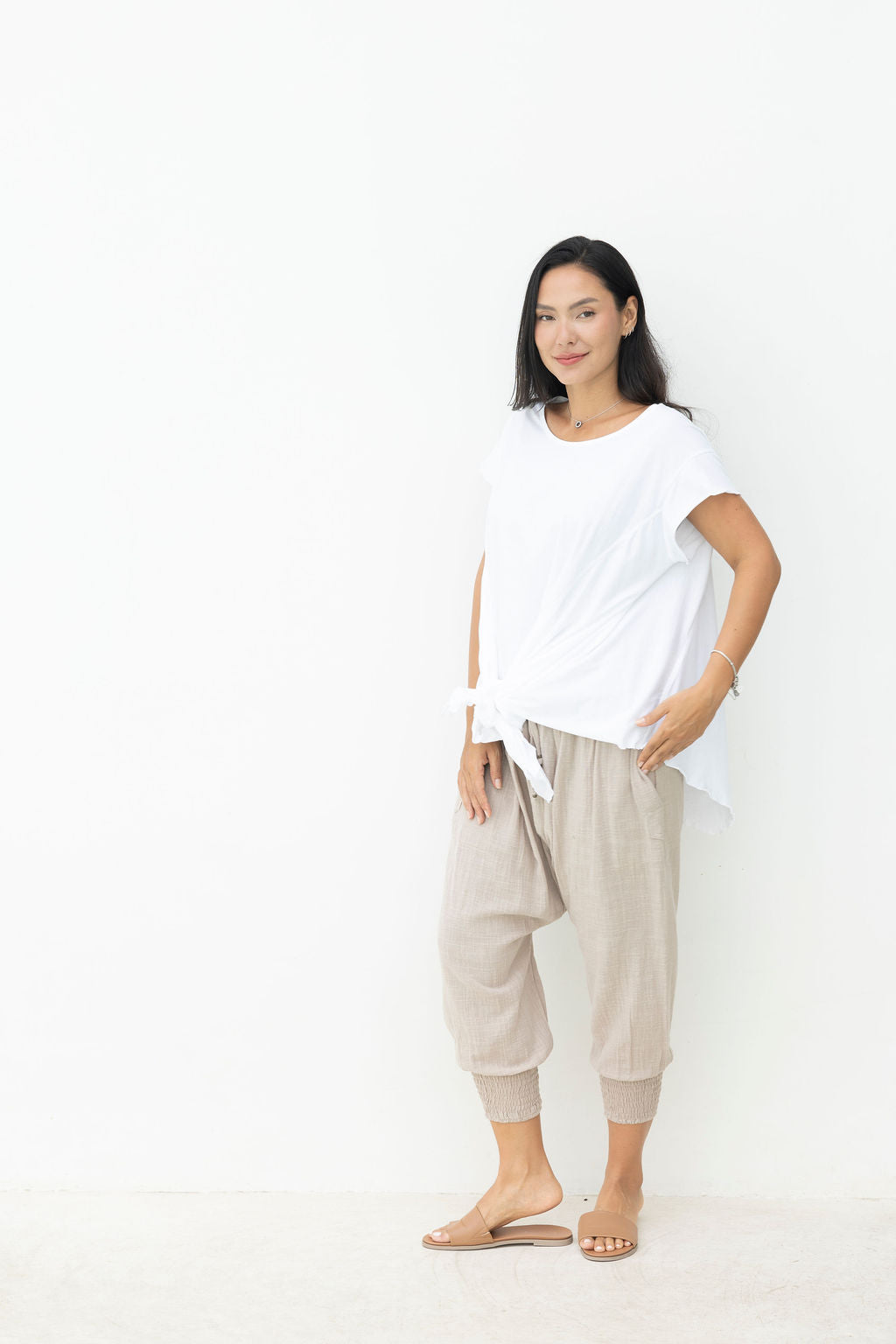 Woman wearing a white top and beige pants on a white background