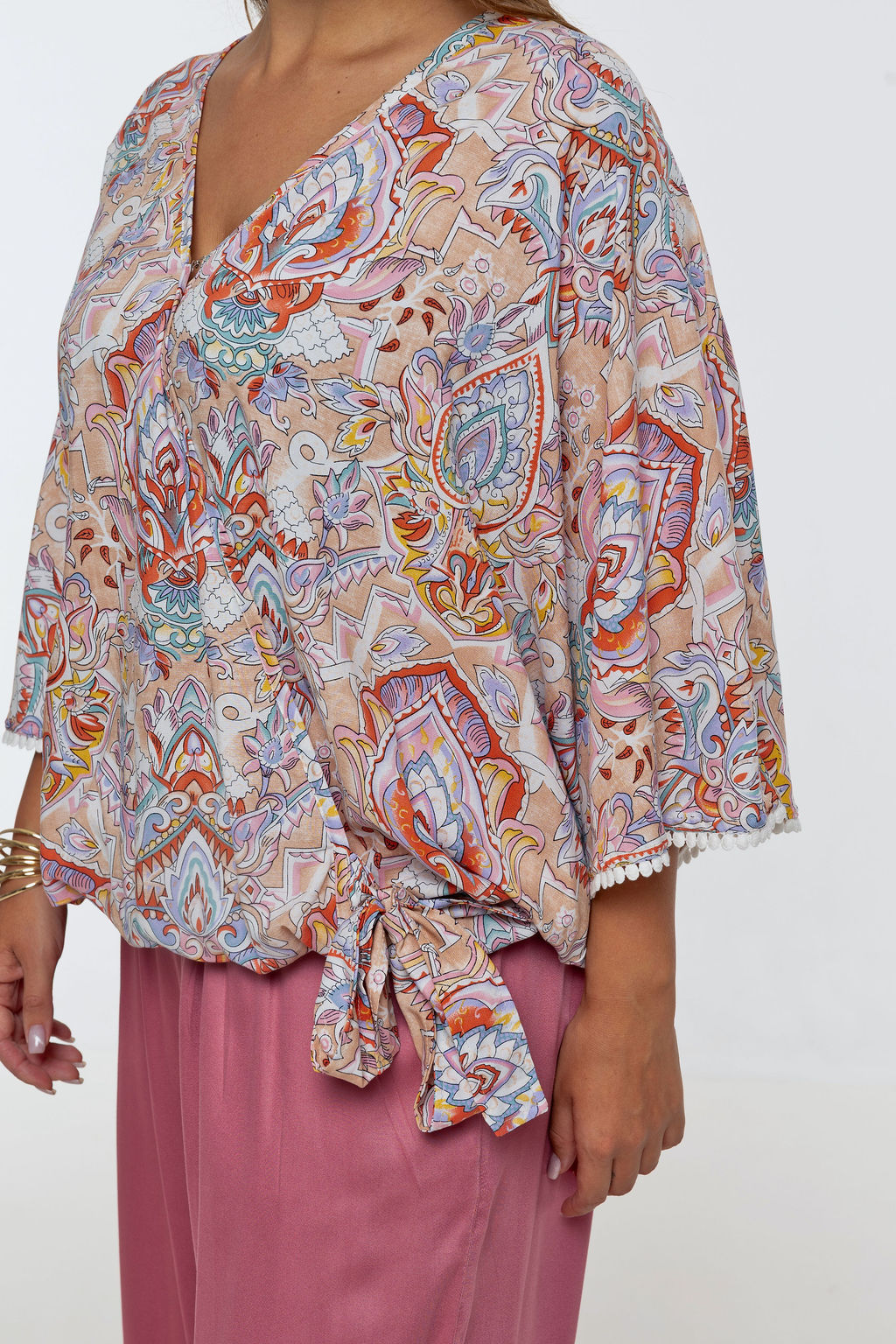 Woman wearing the Messina Top - Palazzo Print. A flowing printed rayon top with a wrap-over neckline, kimono sleeves, crochet trim, elastic waist with adjustable tie