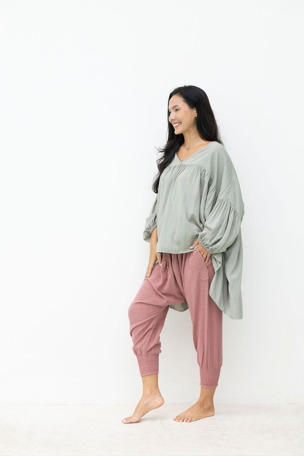 Woman wearing a green top and pink pants on a white background