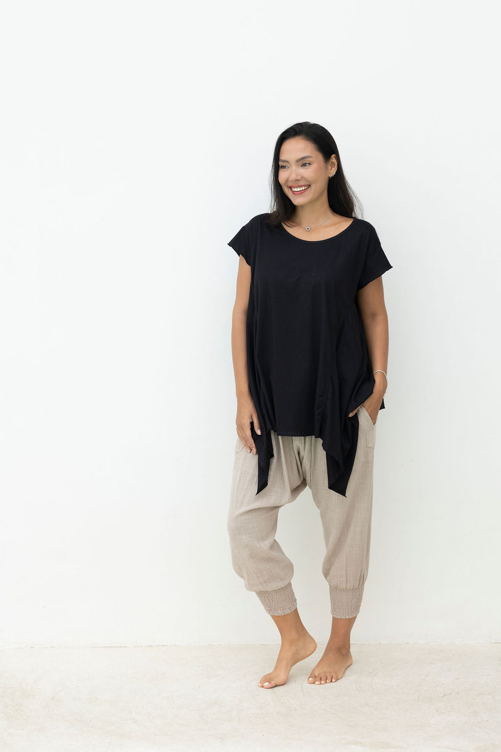 Woman wearing a black top and beige pants on a white background