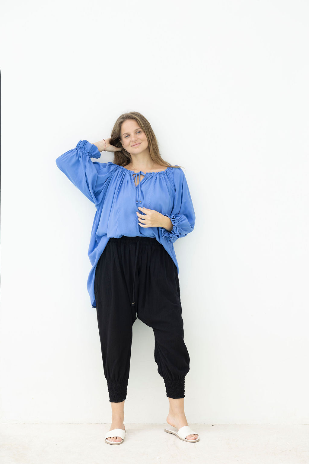 Woman wearing a blue blouse and black pants on a white background