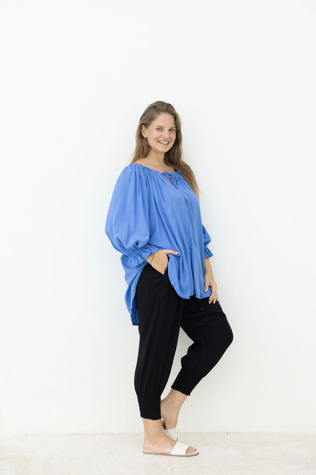 Woman wearing a blue top and black pants on a white background