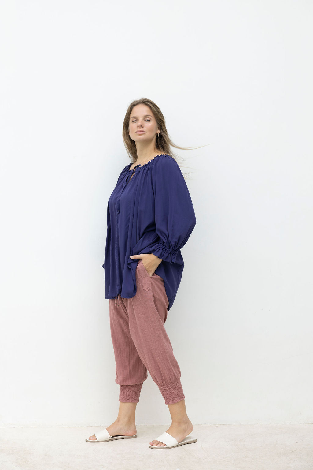 Woman wearing a blue top and pink pants on a white background