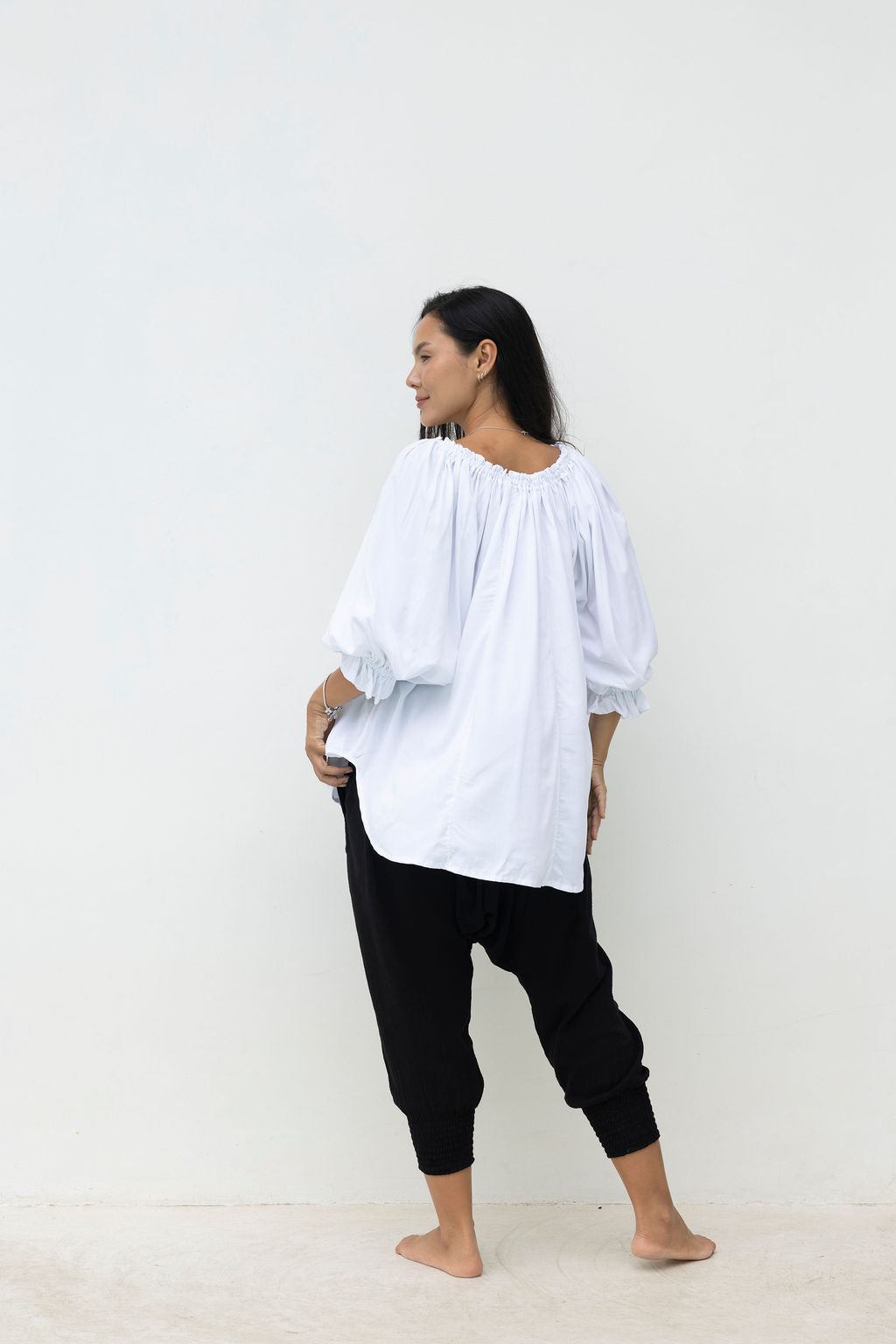 Woman wearing a white blouse and black pants against a white background