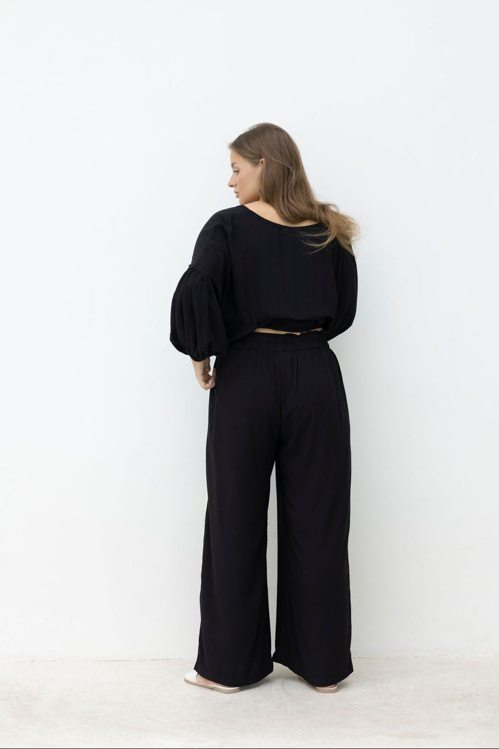 Woman wearing a black outfit against a white background
