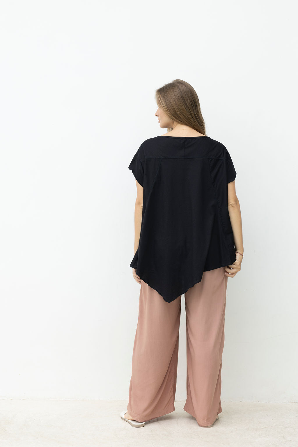 Woman wearing a black top and pink pants on a white background
