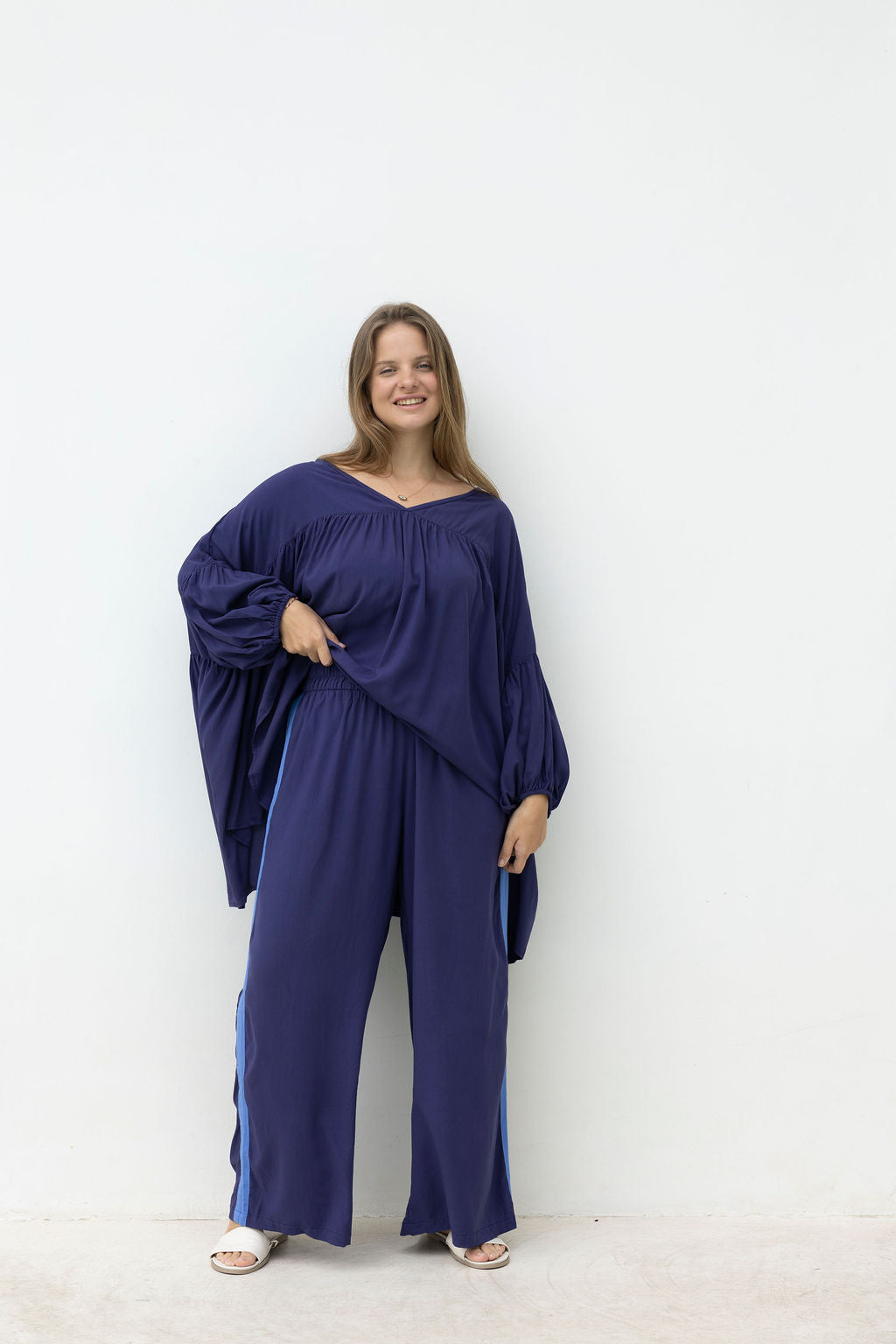 Woman wearing a blue outfit with wide-leg pants on a white background