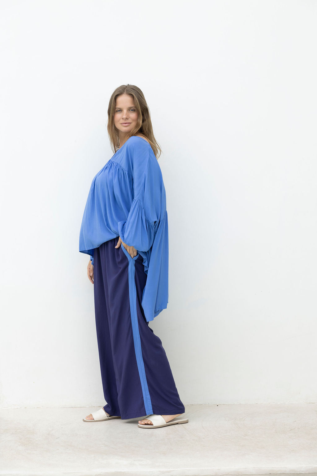 Woman wearing a blue top and navy pants against a white background