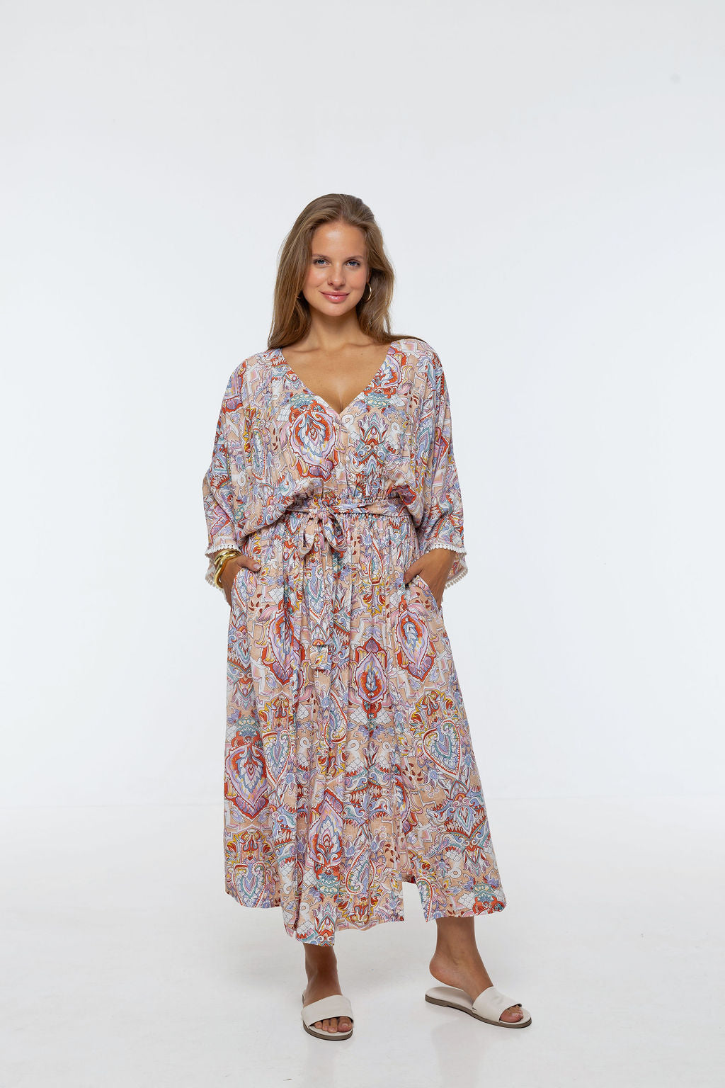 Woman wearing the Bianca Dress in Palazzo Print.  A flowing dress with a wrap-over neckline, elasticated high waist, kimono sleeves and front split.