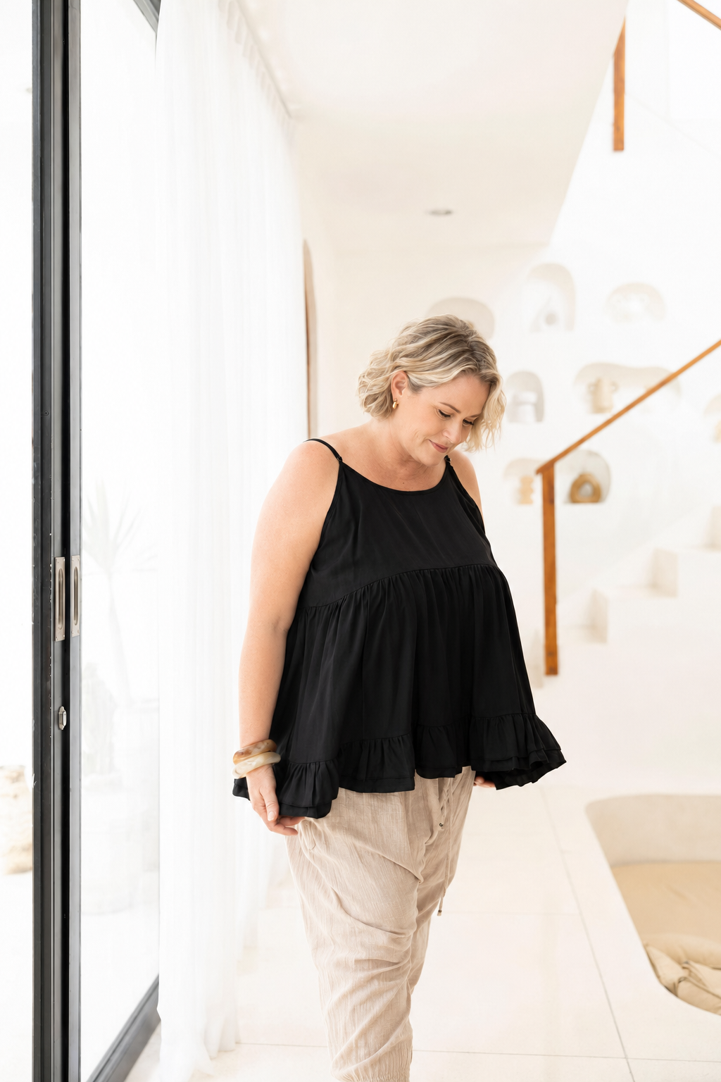 Woman wearing Ipanema Cami in Black.  Relaxed fit with a ruffle hem. 