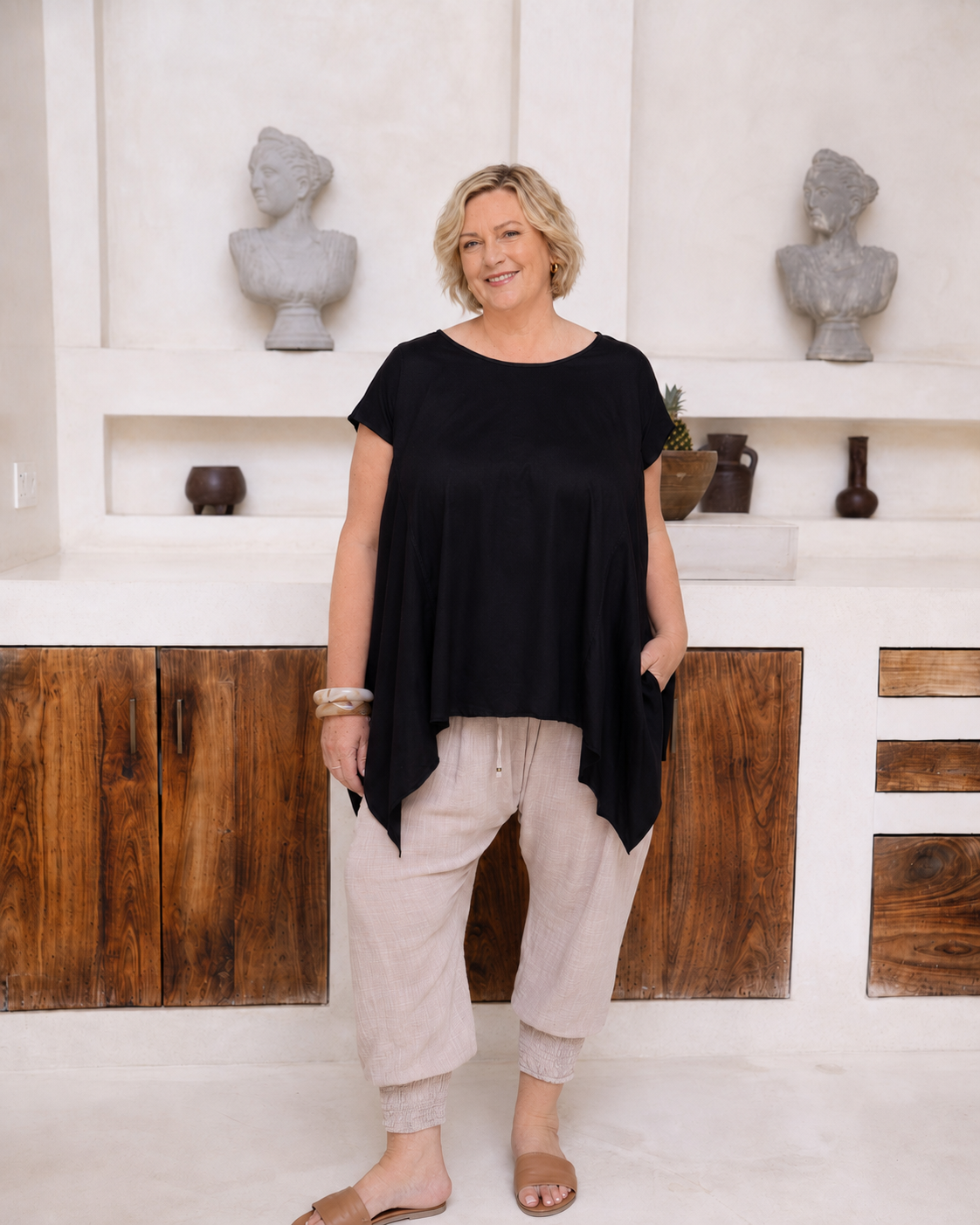Woman wearing Little Cove Top in Black. Relaxed oversized fit, asymmetric hemline, 100% cotton.