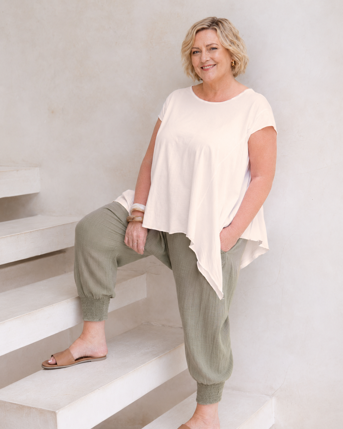Woman wearing Little Cove Top in Cream. Relaxed oversized fit, asymmetric hemline, 100% cotton.