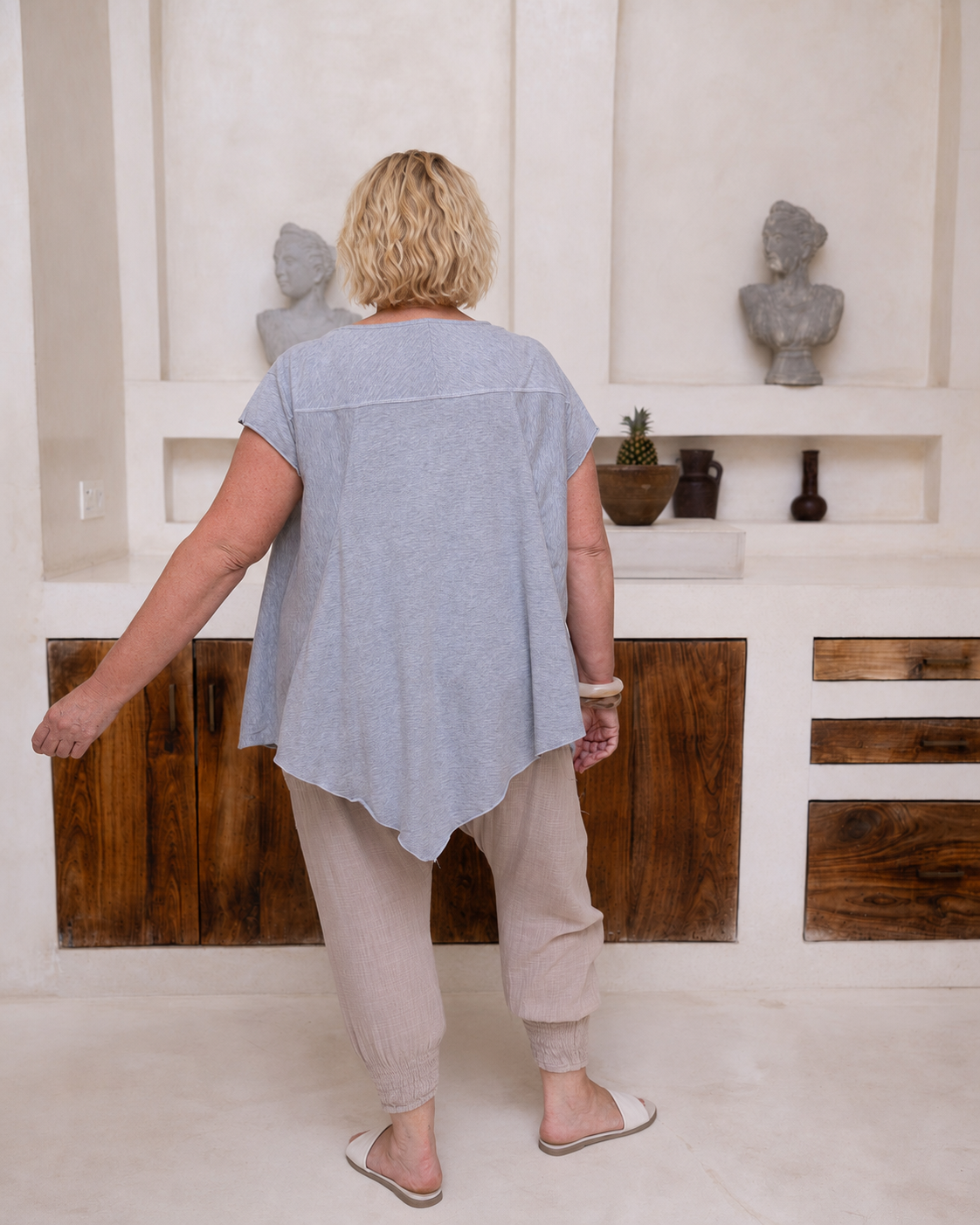 Woman wearing Little Cove Top in Grey Marle. Relaxed oversized fit, asymmetric hemline, 100% cotton.