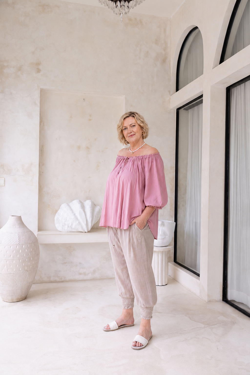 Woman wearing Ouvea Blouse in Dusty Pink, relaxed fit, on or off-shoulder styling