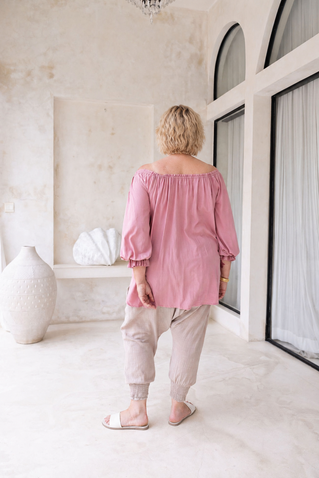 Woman wearing Ouvea Blouse in Dusty Pink, relaxed fit, on or off-shoulder styling
