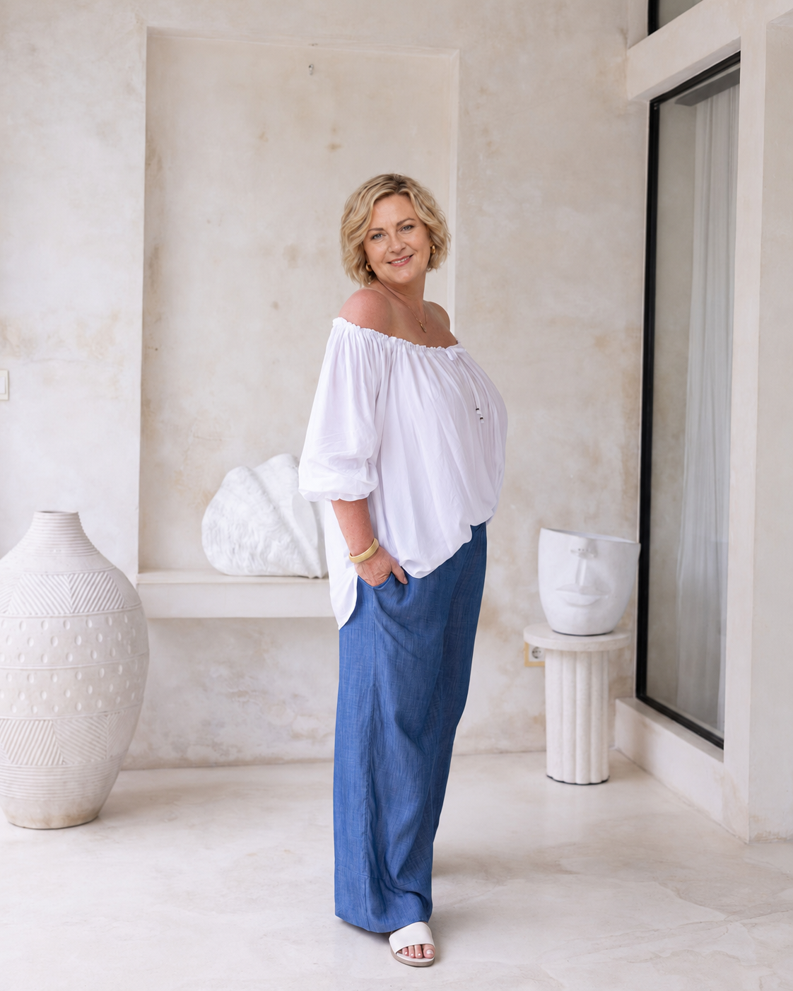 Woman wearing Ouvea Blouse in White, relaxed fit, on or off-shoulder styling