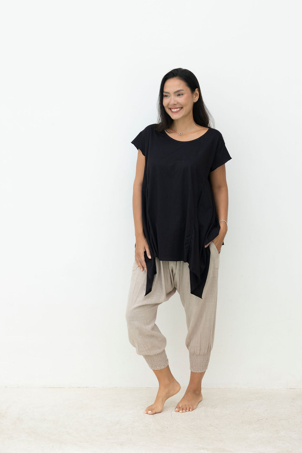 Woman wearing a black top and beige pants on a white background