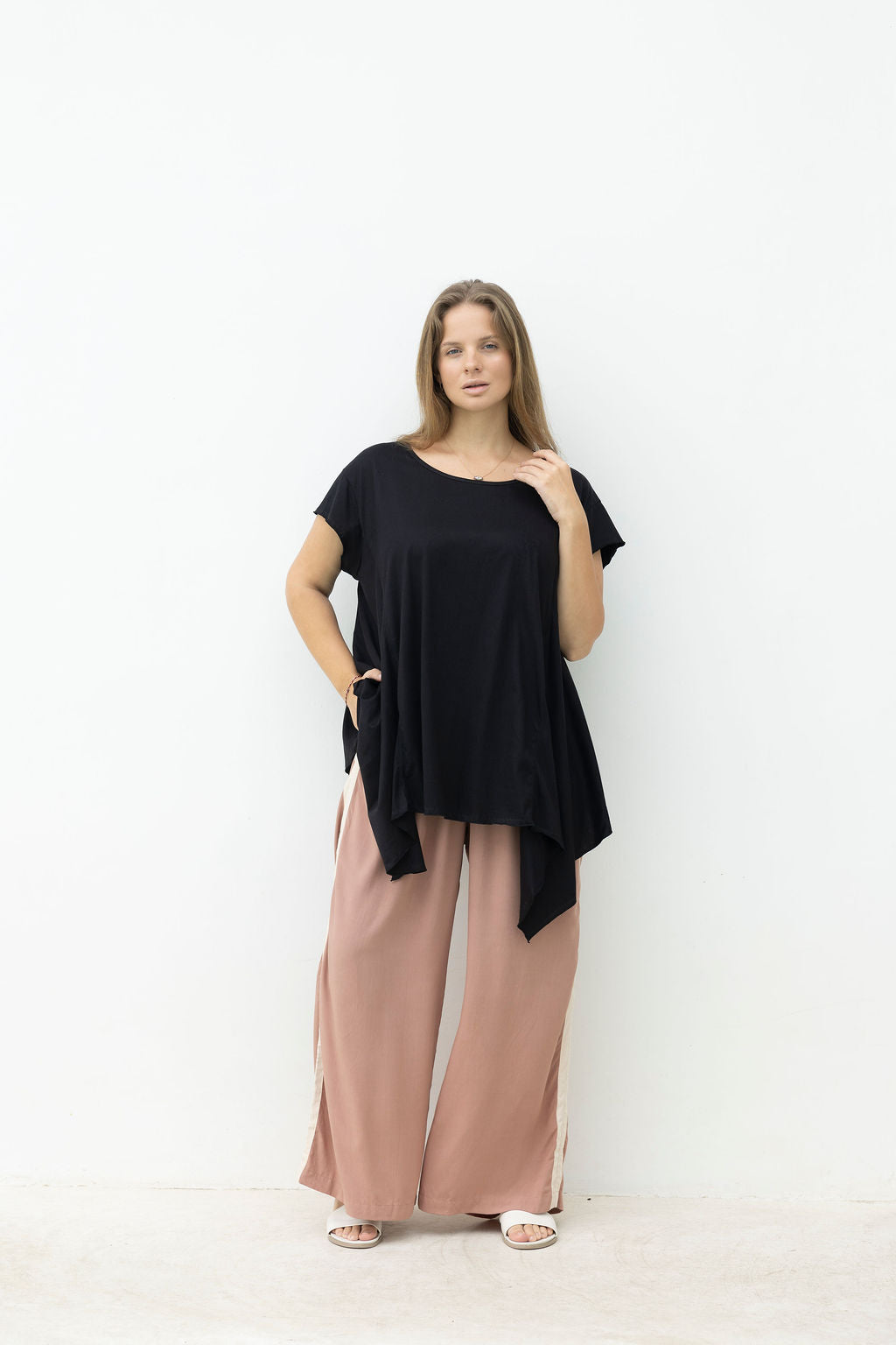Woman wearing a black top and pink pants on a white background