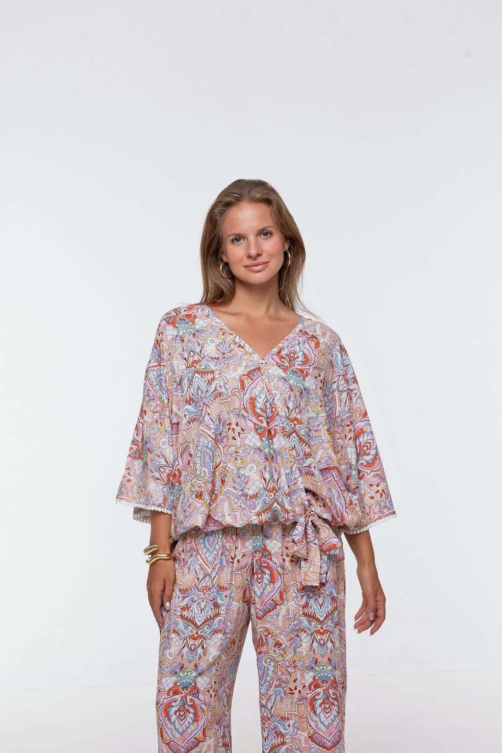 Woman wearing the Messina Top - Palazzo Print.  A flowing printed rayon top with a wrap-over neckline, kimono sleeves, crochet trim, elastic waist with adjustable tie