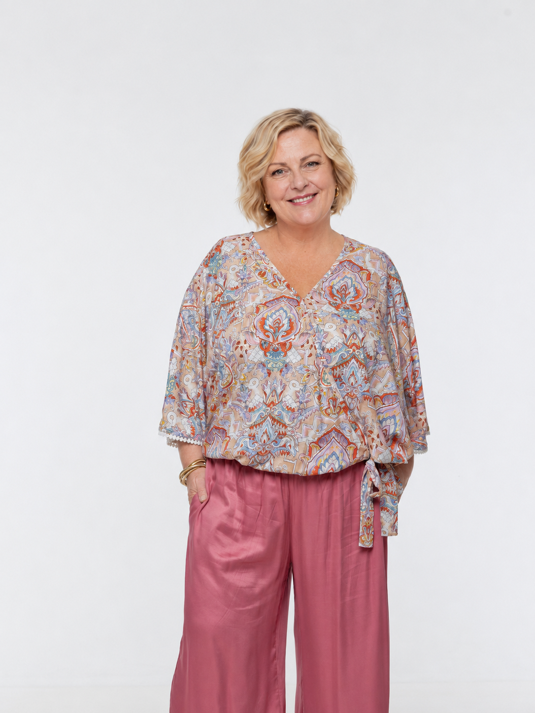 Woman wearing the Messina Top - Palazzo Print.  A flowing printed rayon top with a wrap-over neckline, kimono sleeves, crochet trim, elastic waist with adjustable tie