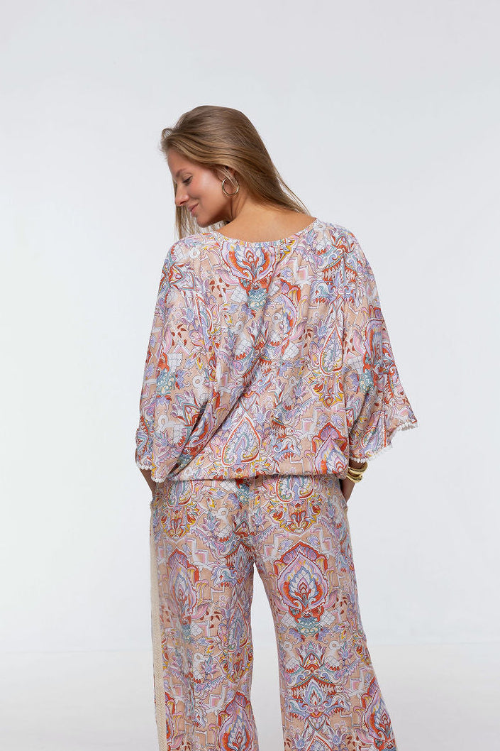 Woman wearing the Messina Top - Palazzo Print.  A flowing printed rayon top with a wrap-over neckline, kimono sleeves, crochet trim, elastic waist with adjustable tie