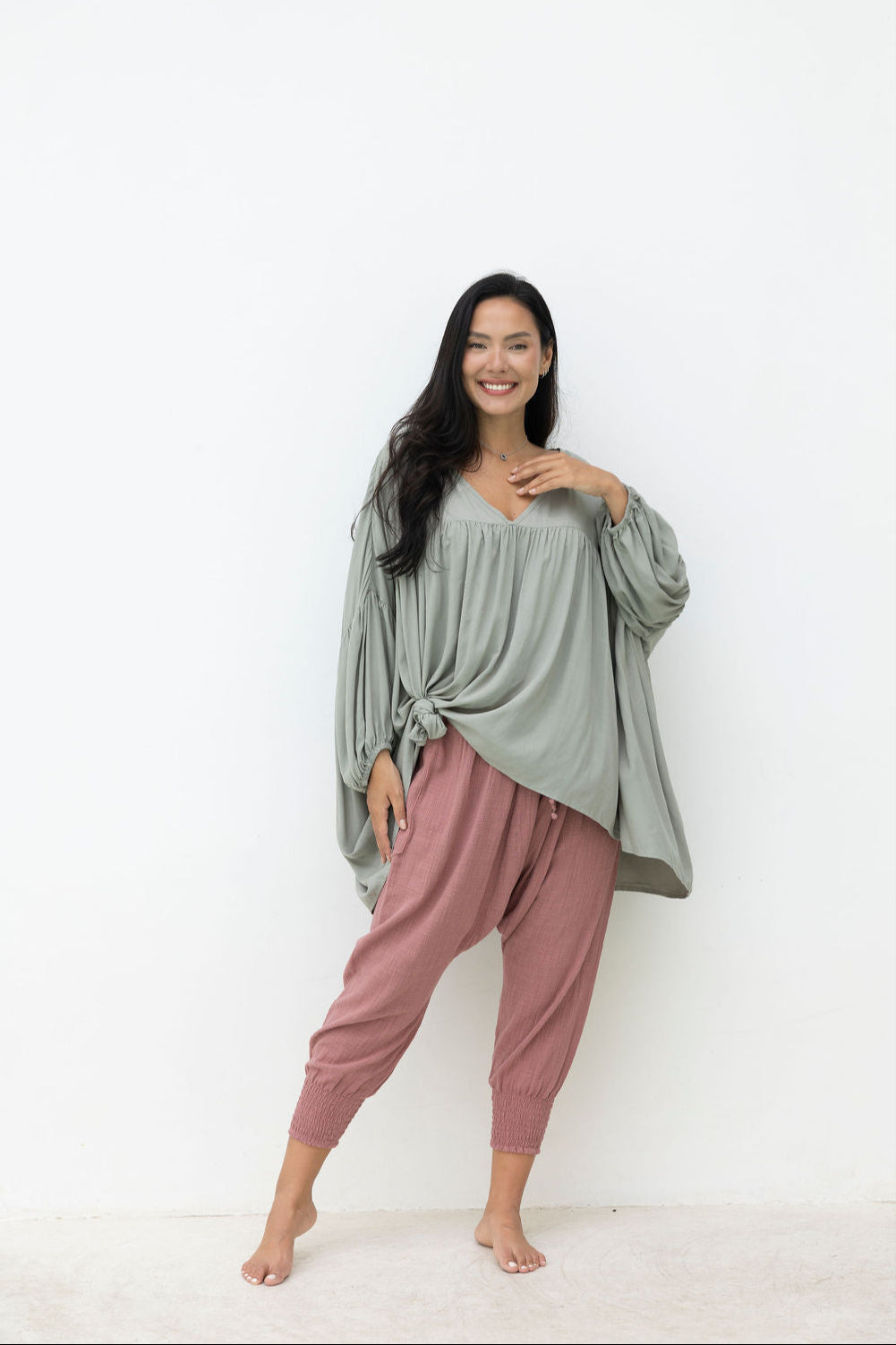 Woman wearing a green top and pink pants on a white background