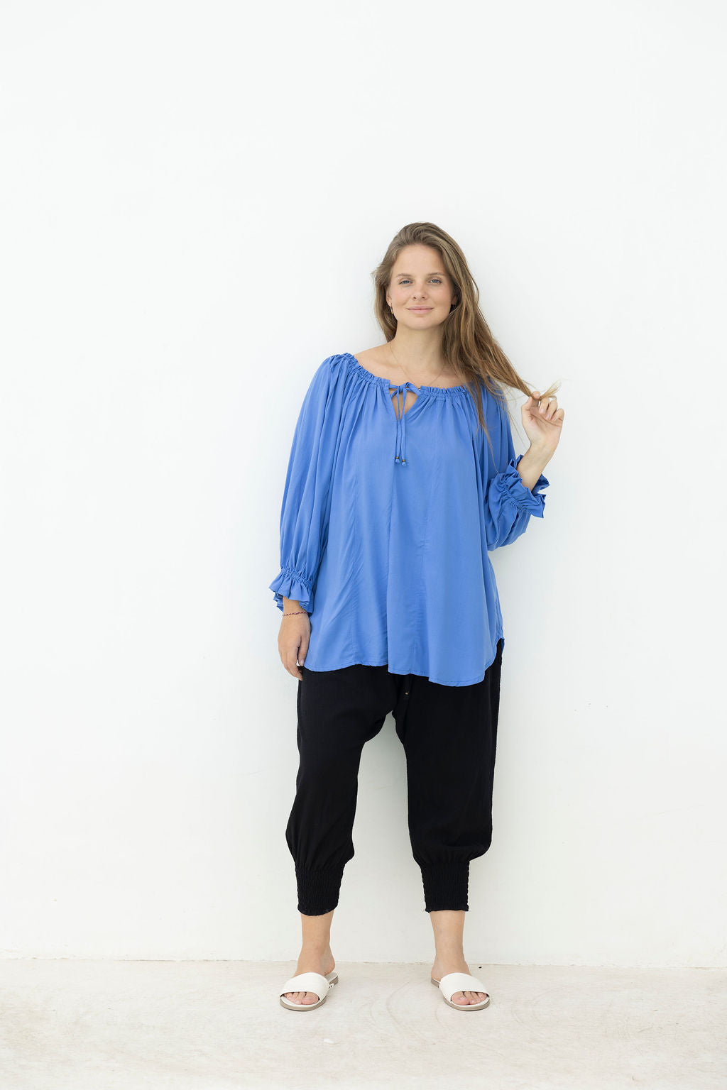 Woman wearing a blue top and black pants on a white background