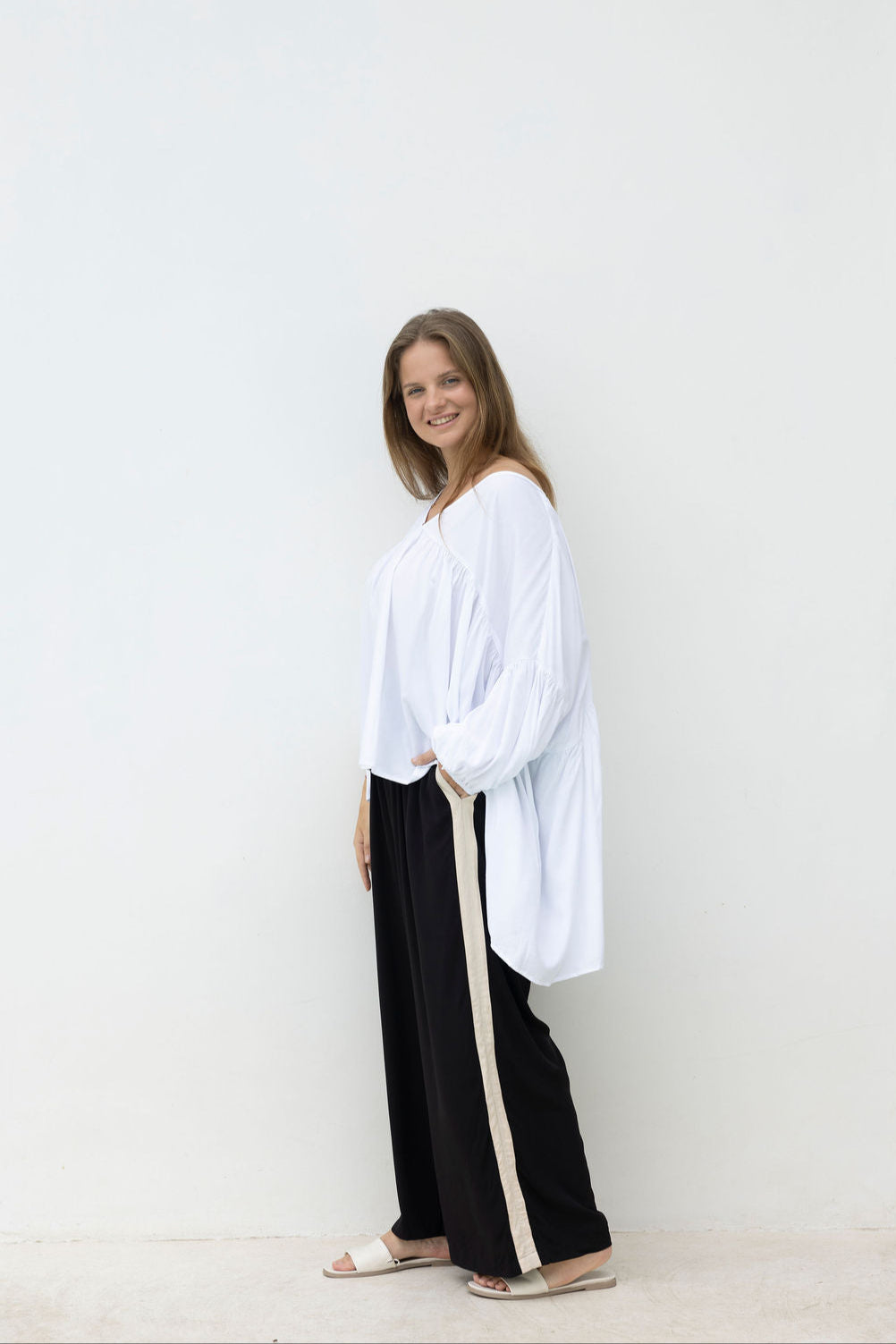 Woman wearing a white blouse and black pants with a white background