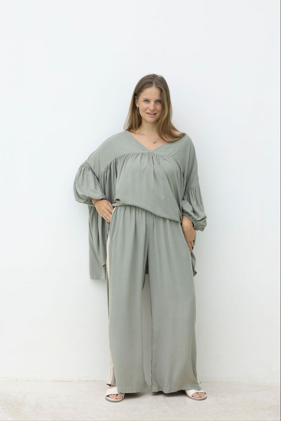 Woman wearing a light green outfit standing against a white background